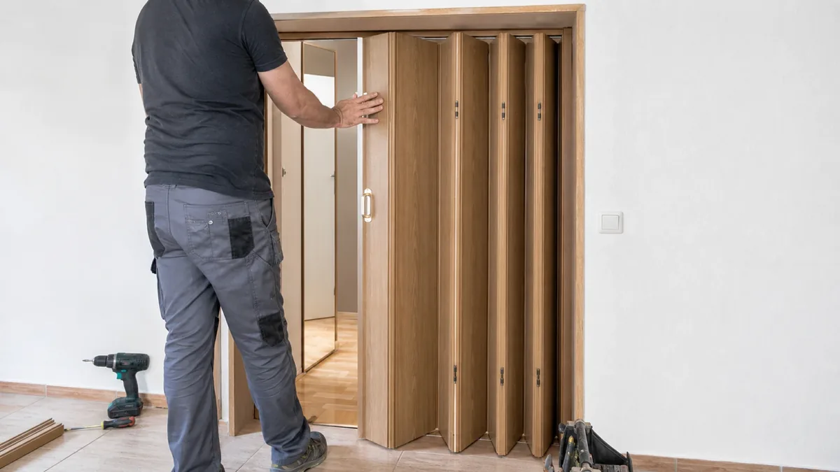 Puerta plegable de madera lacada en blanco montada en un pasillo estrecho